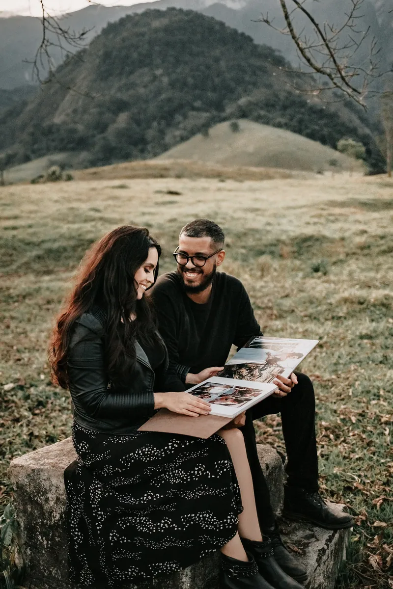 Casal sentado numa pedra folheando o álbum