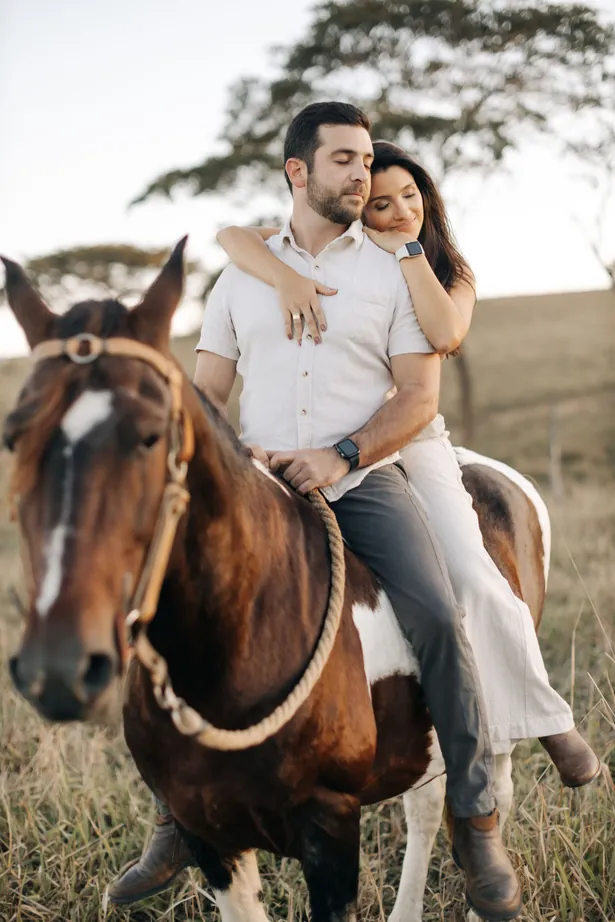 Casal montado num cavalo no campo